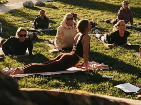 Clase de yoga al aire libre con varias personas en postura de la cobra sobre sus mats